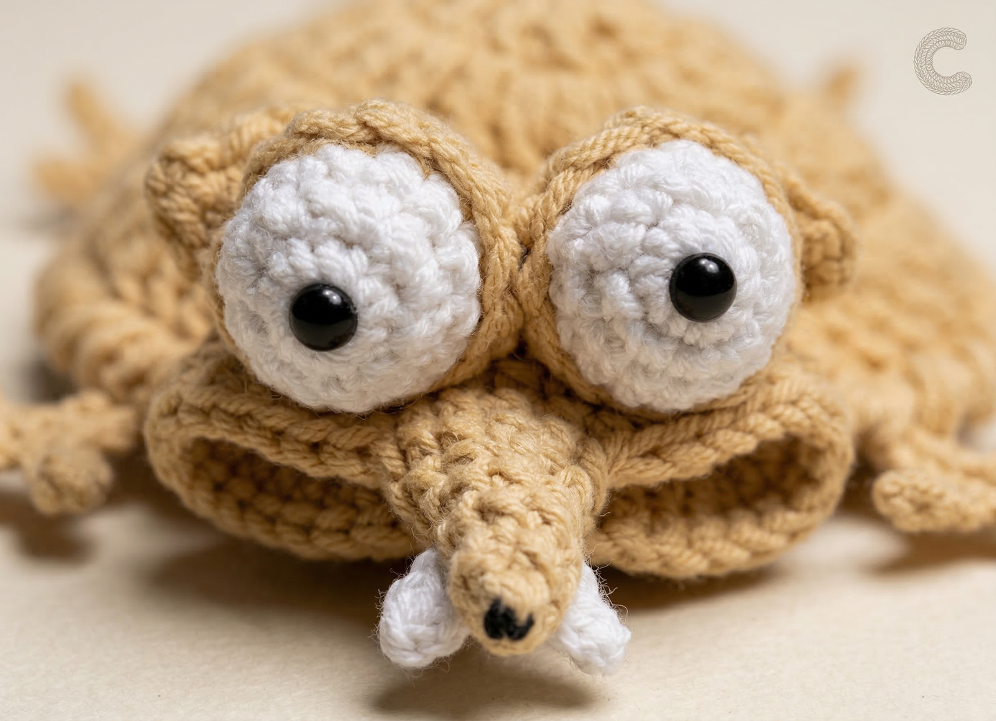 Crocheted toy resembling a turtle with large eyes on a beige background