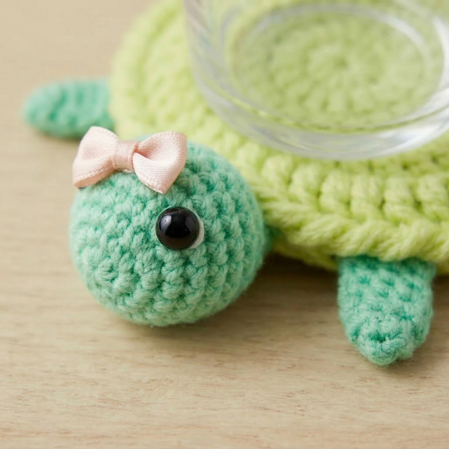 Crocheted turtle with a pink bow on a wooden surface